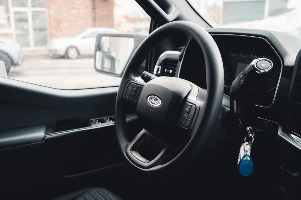 pexels-photo-16094585 Interior view of a Ford vehicle showing steering wheel, dashboard, and car keys for modern automotive design.